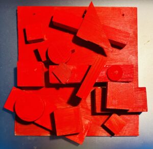 ベニヤ板に木片を並べて全体を赤い色で丁寧に塗りました。